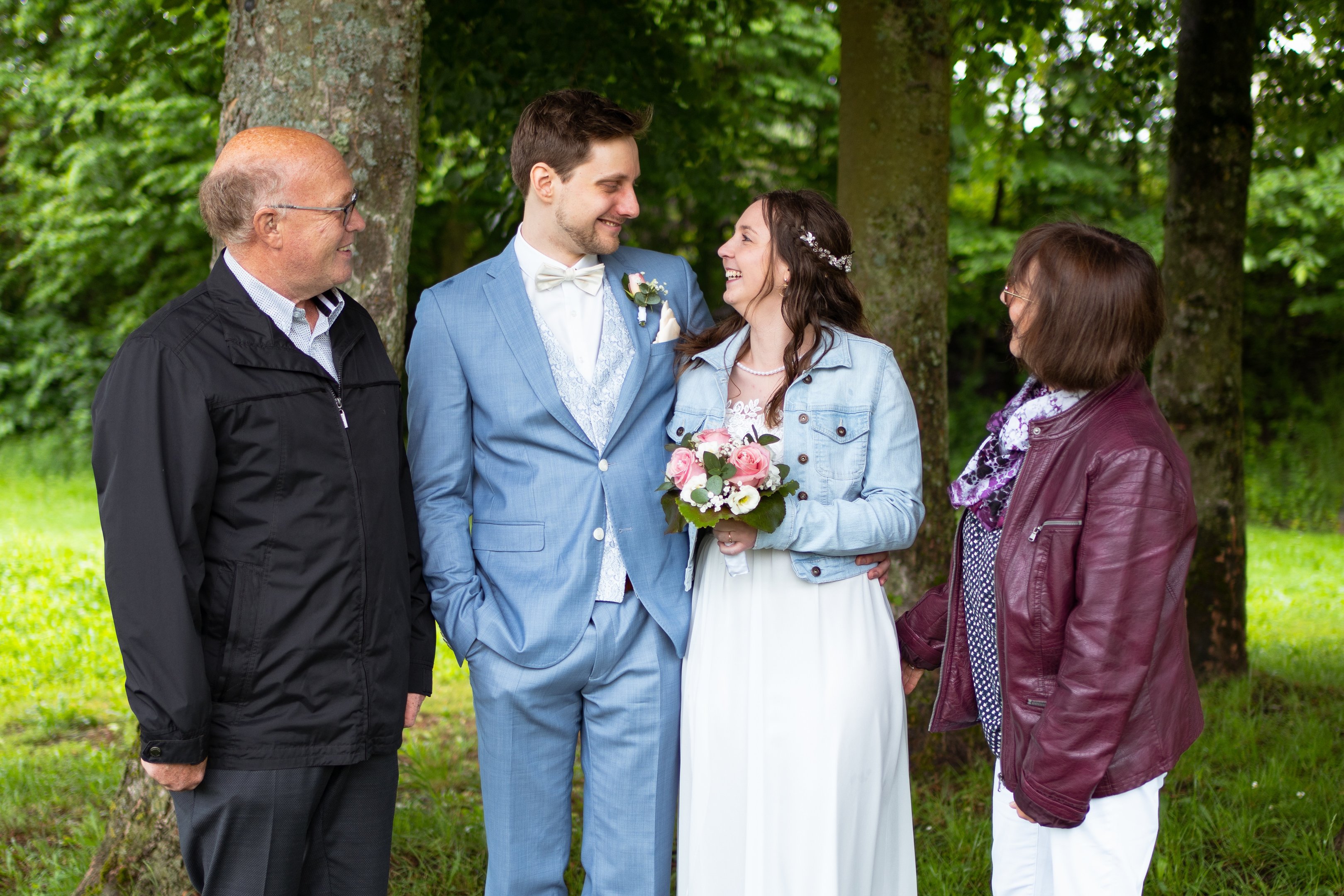 Hochzeitsfoto: Gruppenfoto mit Hochzeitspaar und Familie schauen lachend auf das Paar