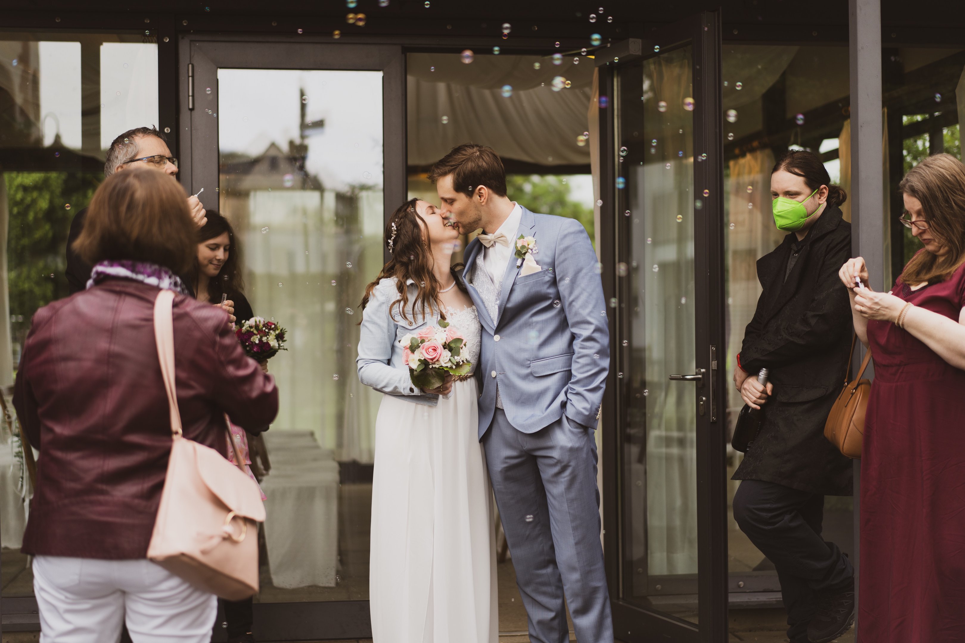 Hochzeitsfoto: Foto vom küssenden Brautpaar und Gästen beim Auszug aus dem Standesamt