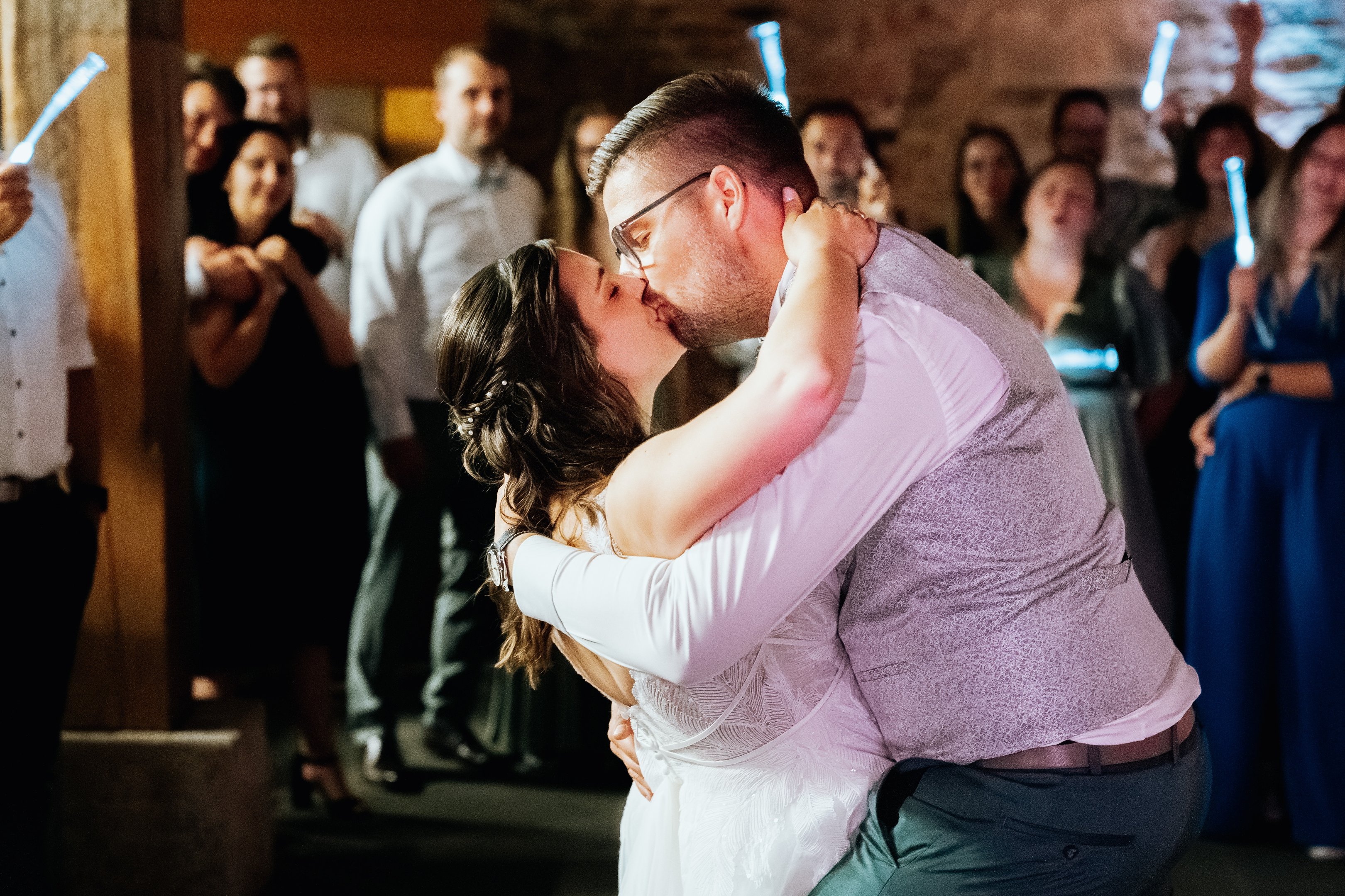 Hochzeitspaar bei ihrem Hochzeitstanz: zu sehen ist das Paar wie es sich küsst inmitten der Gäste