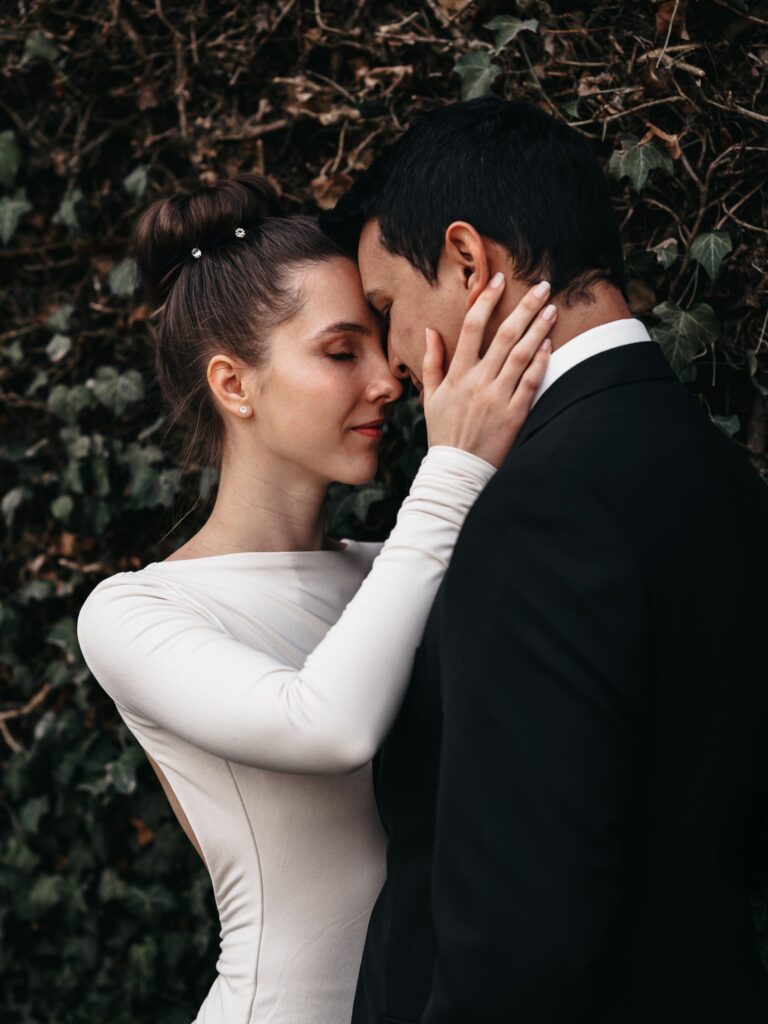 Hochzeitsfoto von Braut und Bäutigam halten sich in den Armen vor einem grünen Laubhintergrund