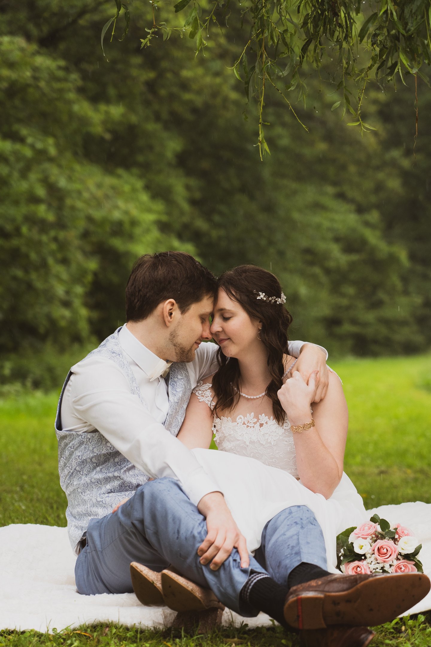 Brautpaar sitzt bei einander in der Natur, halten sich im Arm